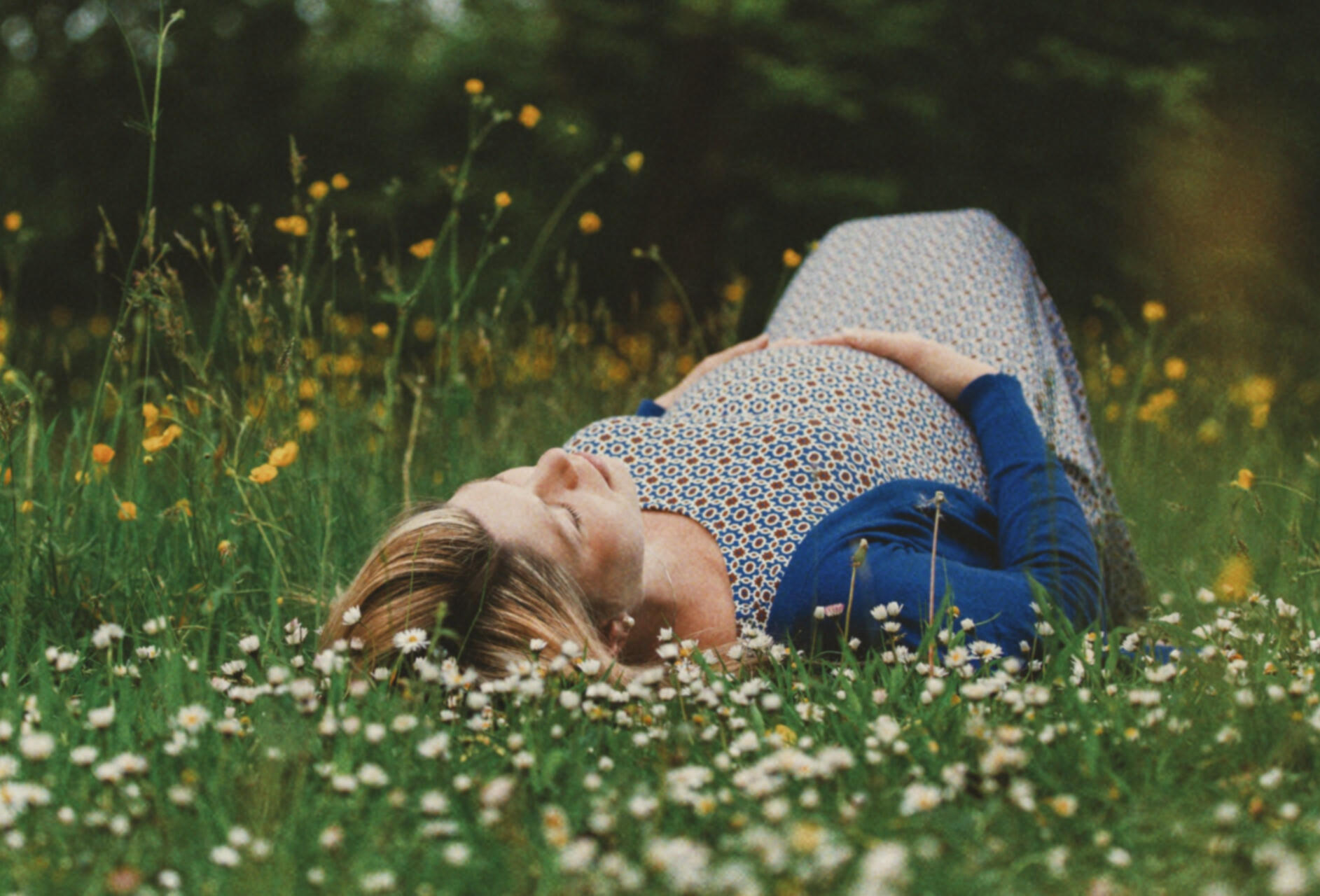 a beautiful professional image of a pregnant young woman lying in a field in Lincoln